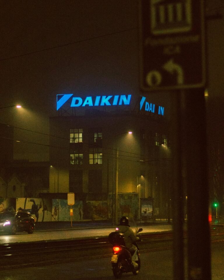 A foggy urban street at night featuring neon city lights and a lone rider.
