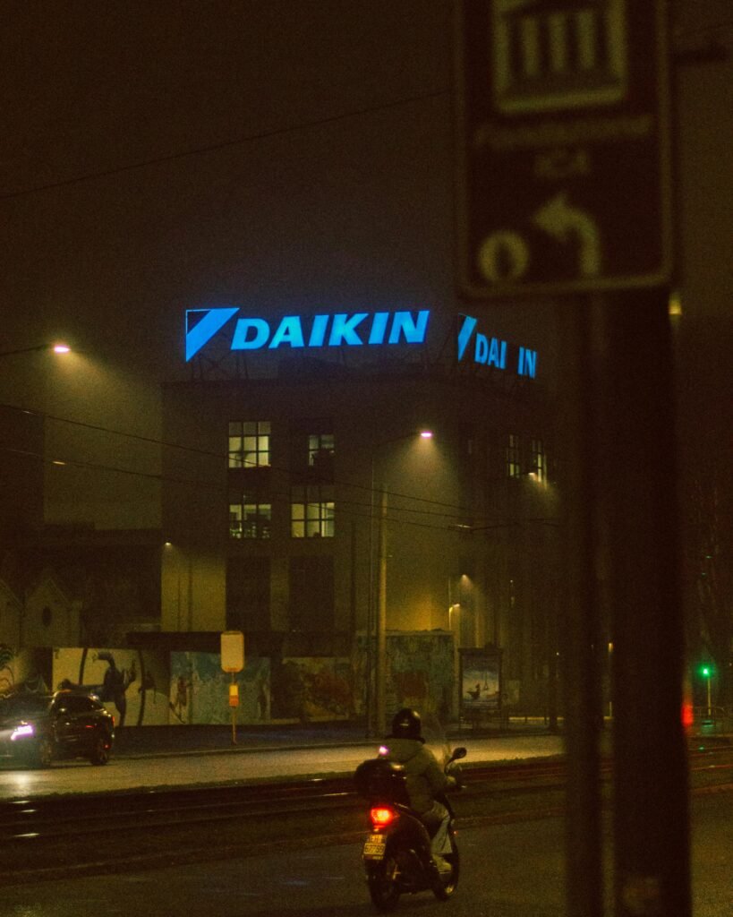 A foggy urban street at night featuring neon city lights and a lone rider.